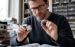 MLCC vs film capacitor - engineer comparing a multilayer ceramic capacitor with a metallized film capacitor on a workbench